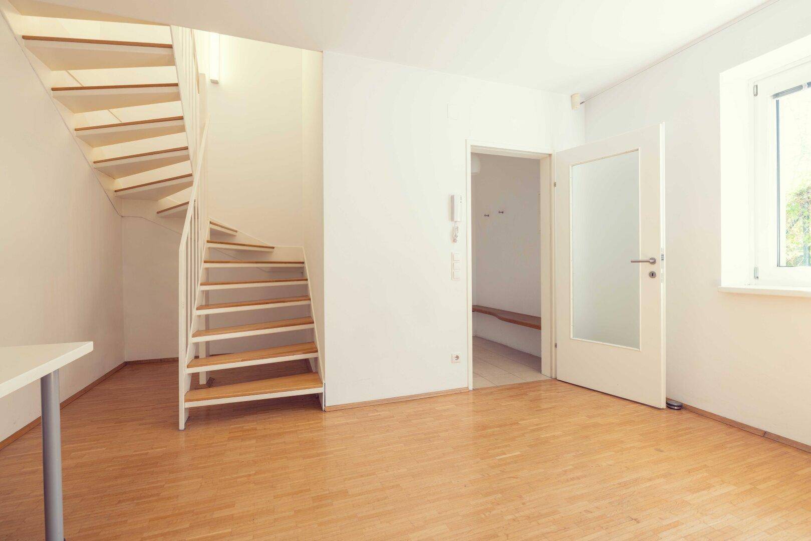Heller Raum mit weißer Wendeltreppe, Holzboden und viel Tageslicht.