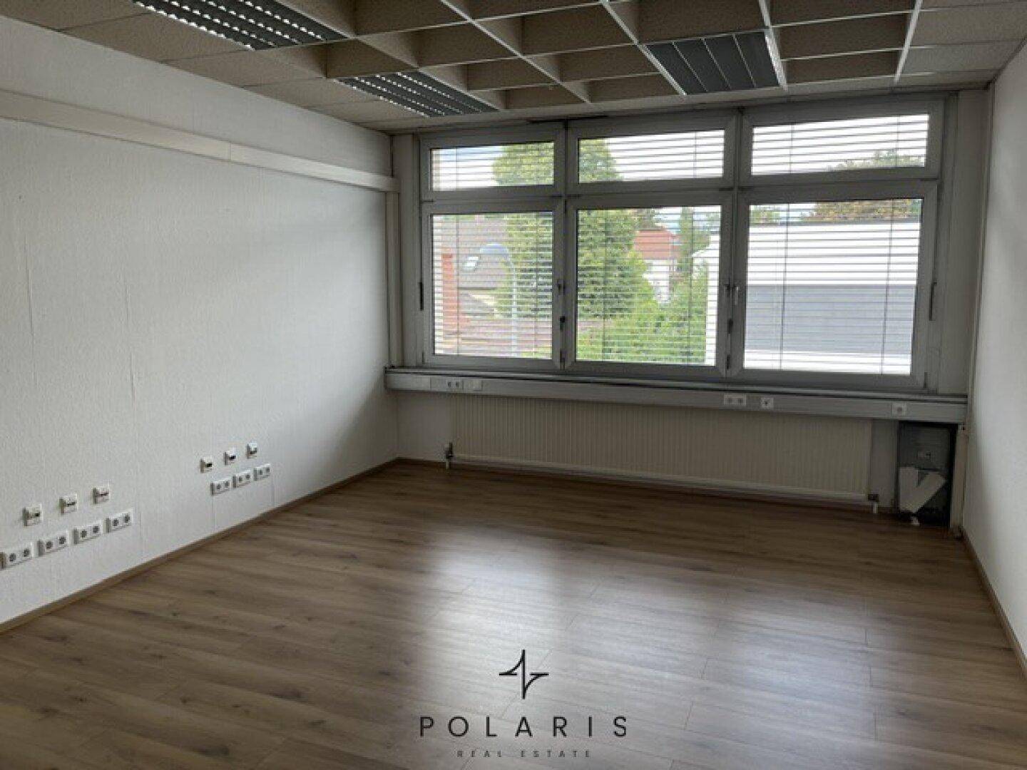 Leeres Büro mit großen Fenstern, Jalousien und Heizkörpern, bietet viel Tageslicht und Ausblick.