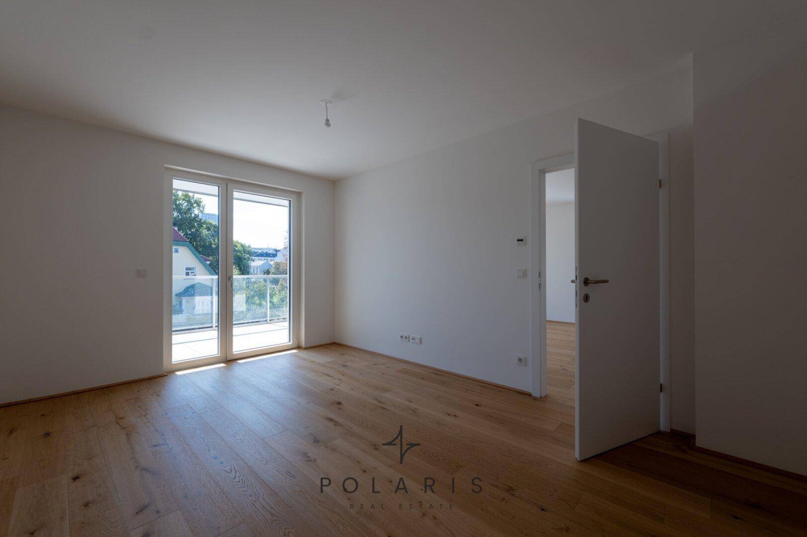 Helles Schlafzimmer mit Holzboden und Zugang zum Balkon, bietet eine angenehme Wohnatmosphäre.