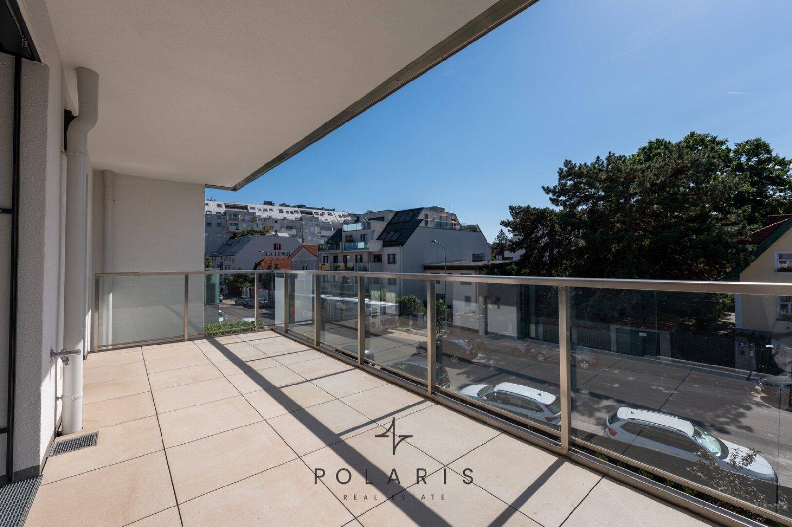 Geräumiger Balkon mit Fliesenboden und Glasgeländer, bietet einen weiten Blick über die Umgebung.