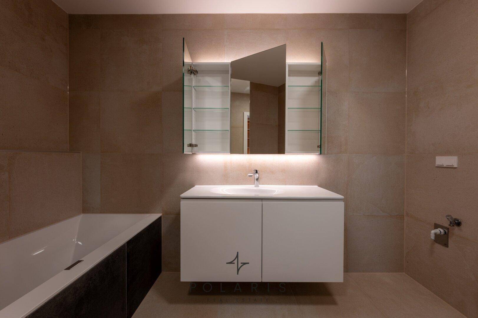 Eleganter Waschtisch mit Spiegelschrank und indirekter Beleuchtung in einem modernen Badezimmer.