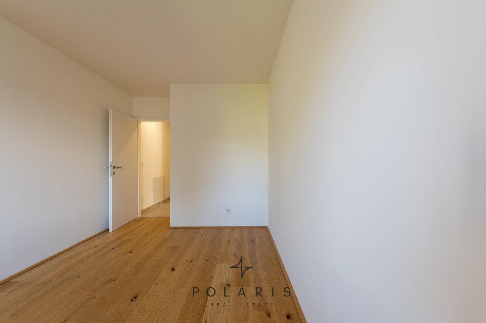 Ruhiges Schlafzimmer mit Holzboden und weißen Wänden, bietet viel Raum für individuelle Gestaltung.
