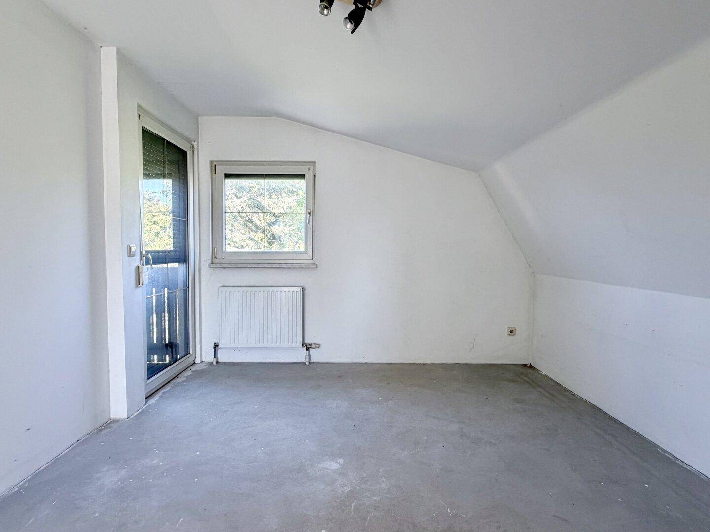 Geräumiges Zimmer mit Fenster und Balkontür, bietet viel Tageslicht und frische Luft.