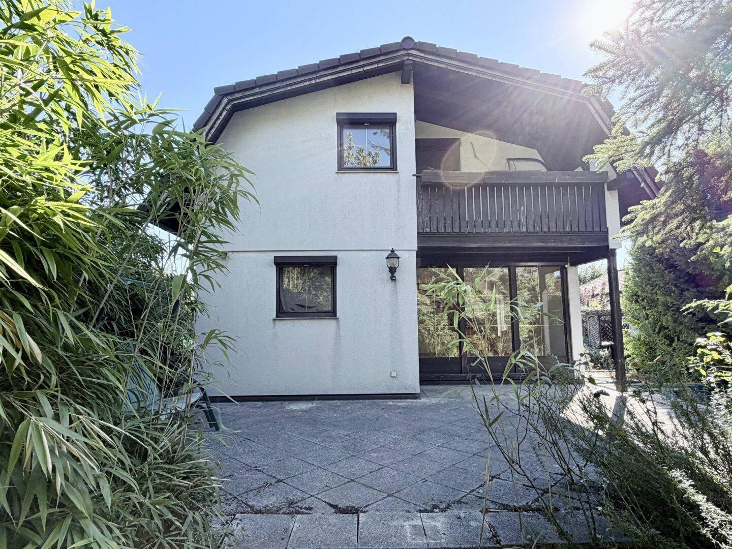 Ansicht des Hauses von der Terrasse, umgeben von üppigem Grün und Bambuspflanzen.