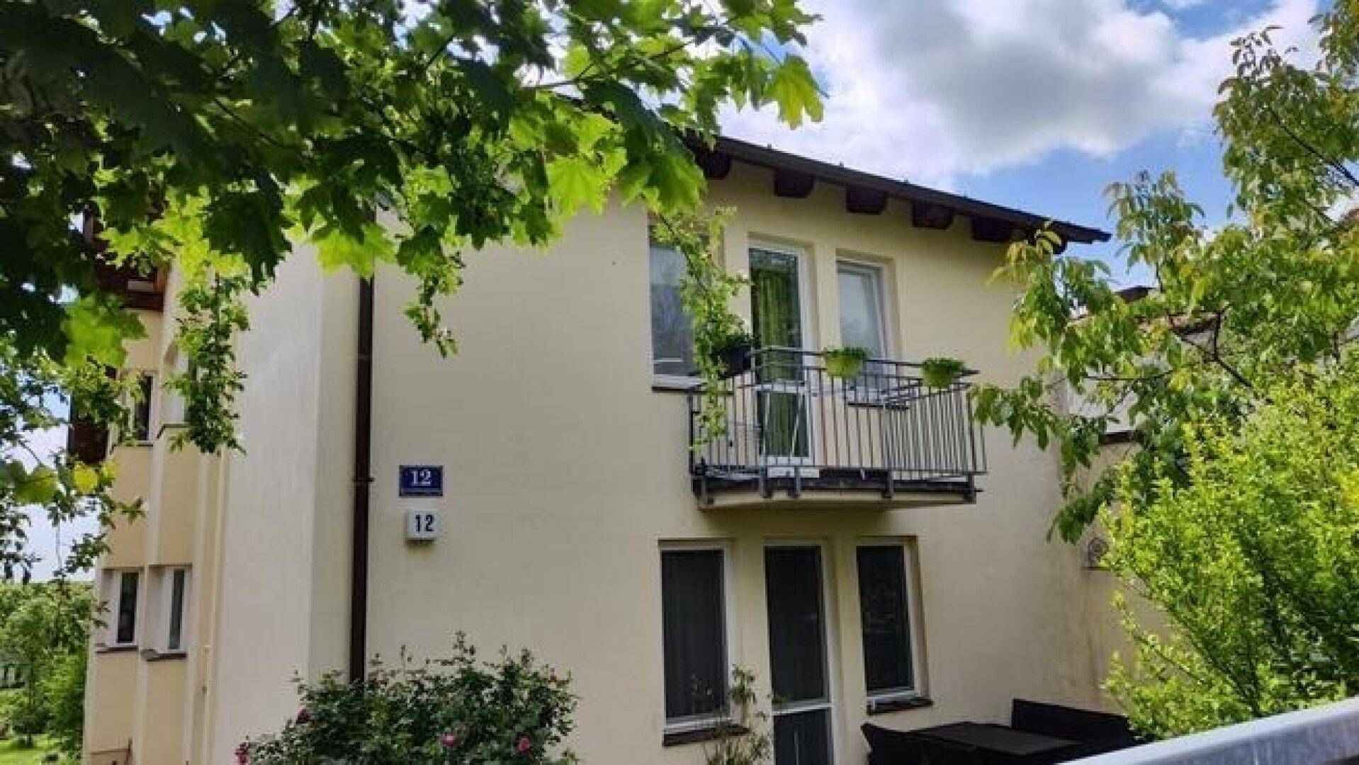 Fassade des Hauses mit kleinem Balkon und schmiedeeisernem Geländer unter blauem Himmel.