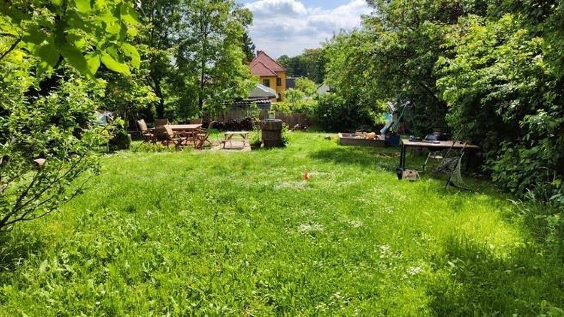 Geräumiger Garten mit Essbereich im Freien, Grillplatz und viel Grünfläche.