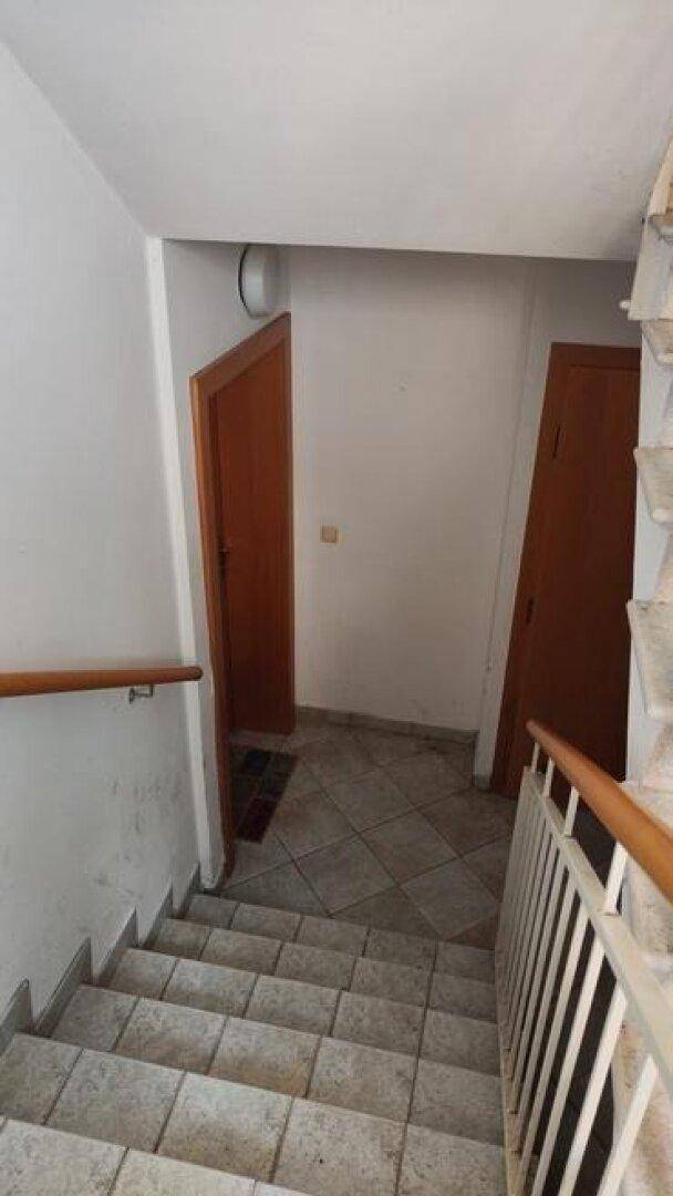Treppenabsatz mit gefliestem Boden, Holztüren und Zugang zu den Wohnungen.