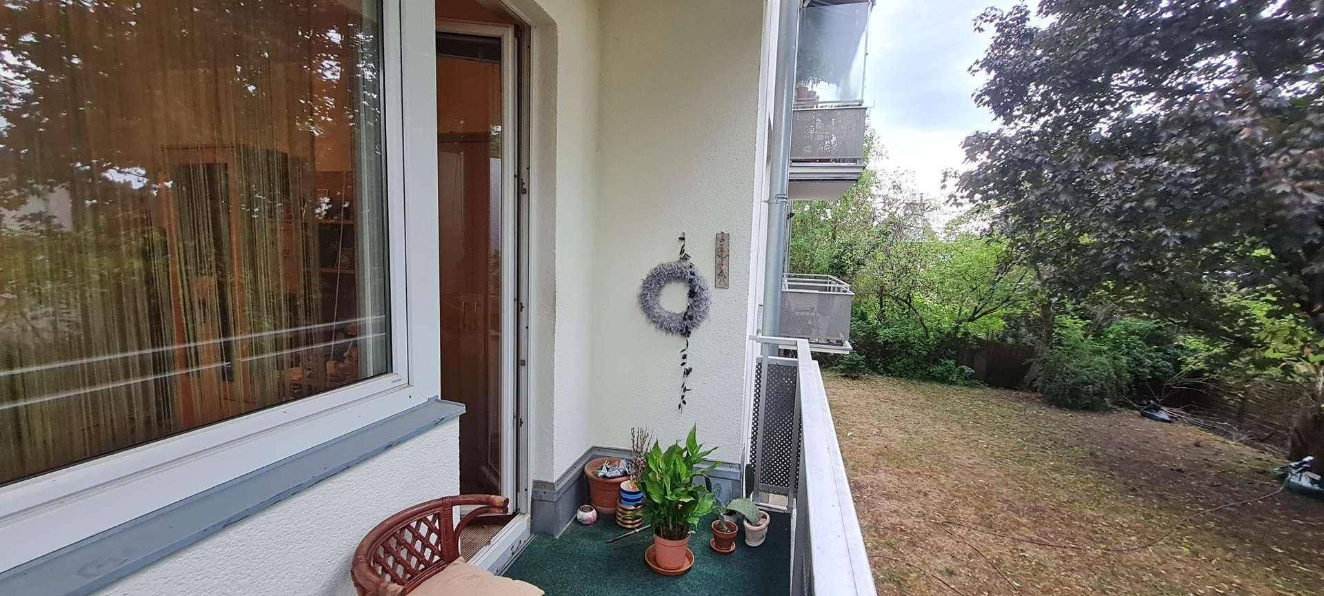 Kleiner Balkon mit Pflanzen und einem Stuhl, bietet Blick ins Grüne.