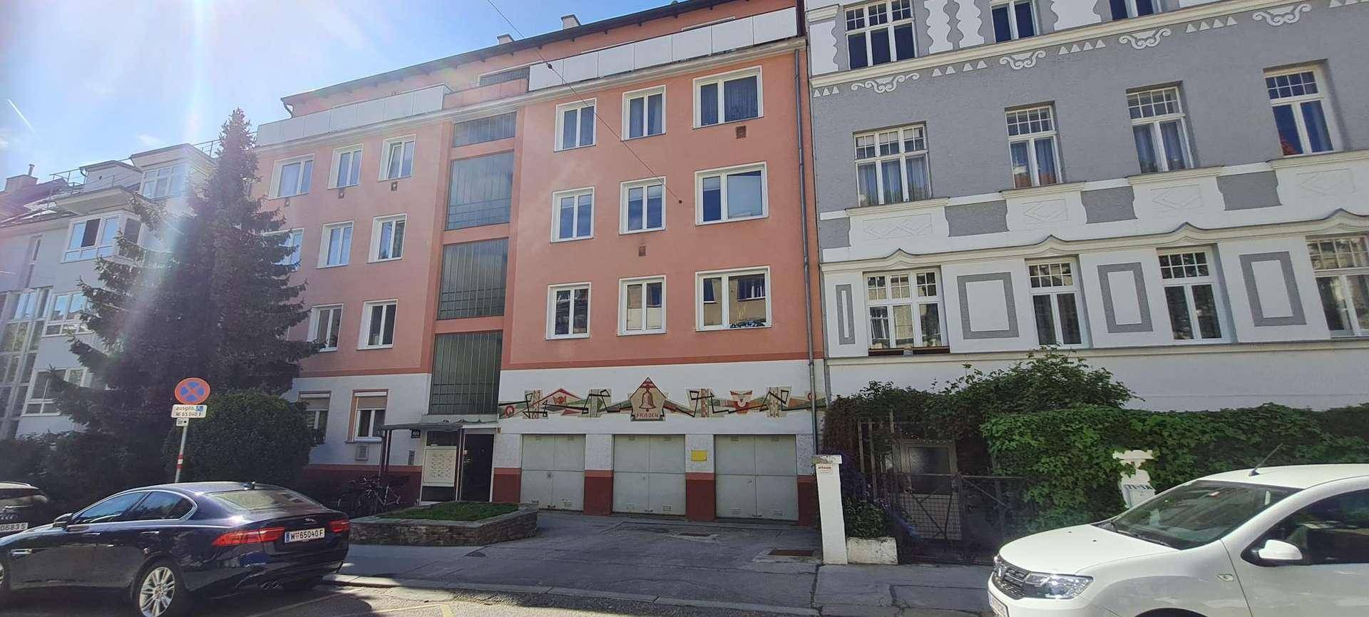 Fassade eines Mehrfamilienhauses mit moderner Architektur und integrierten Garagen im Erdgeschoss.