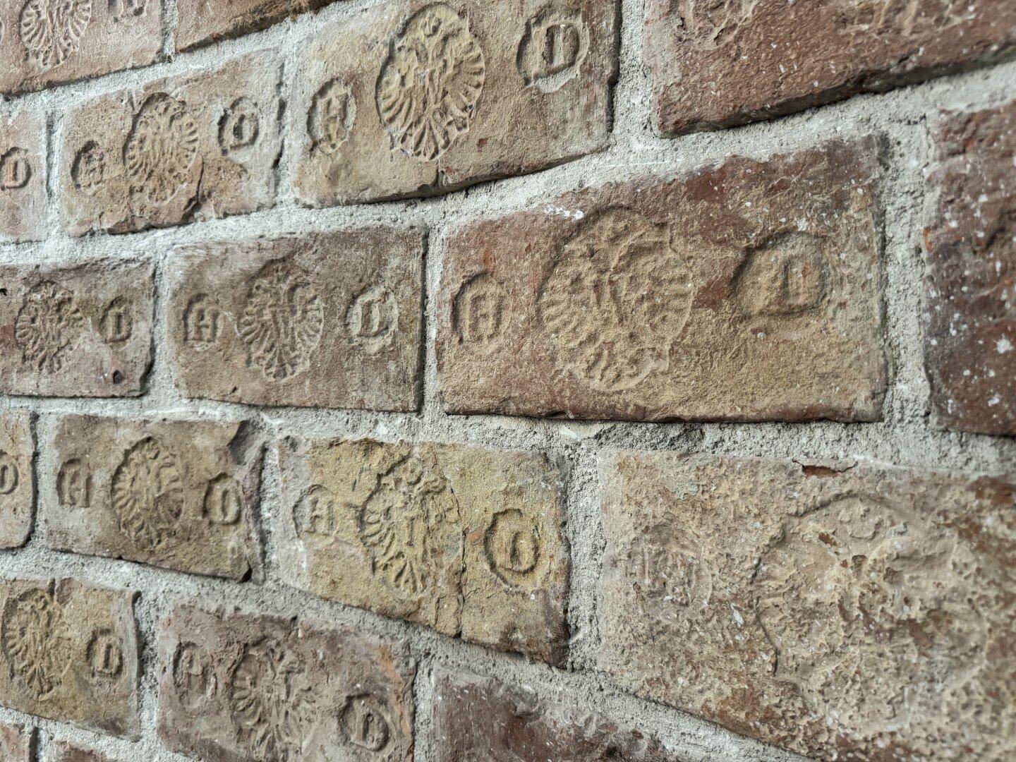 Nahaufnahme einer historischen Ziegelwand mit eingeprägten Mustern, die den Charme des Gebäudes unterstreicht.