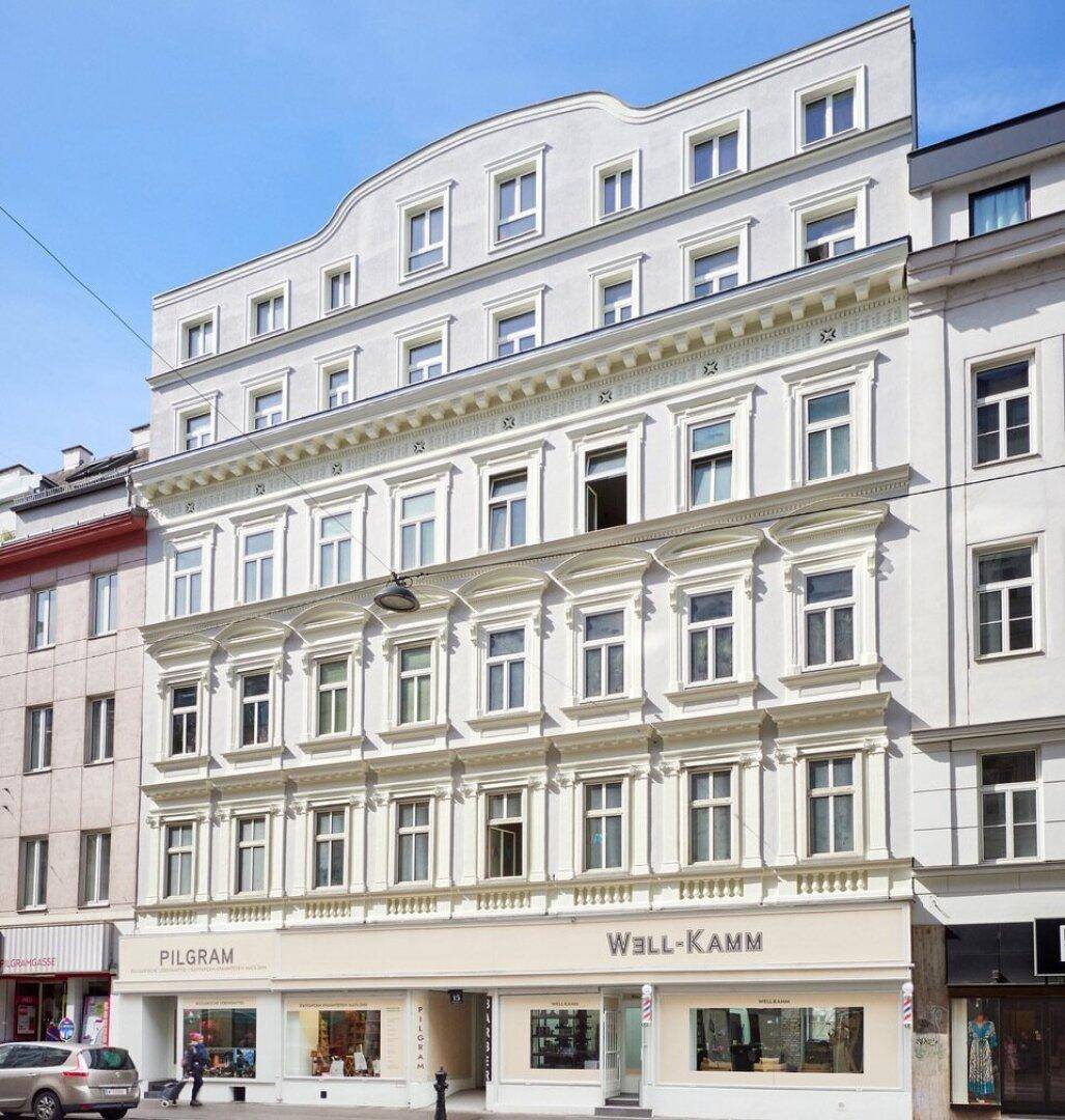 Historisches Gebäude mit klassischer Fassade und Geschäftsflächen im Erdgeschoss in einer städtischen Umgebung.