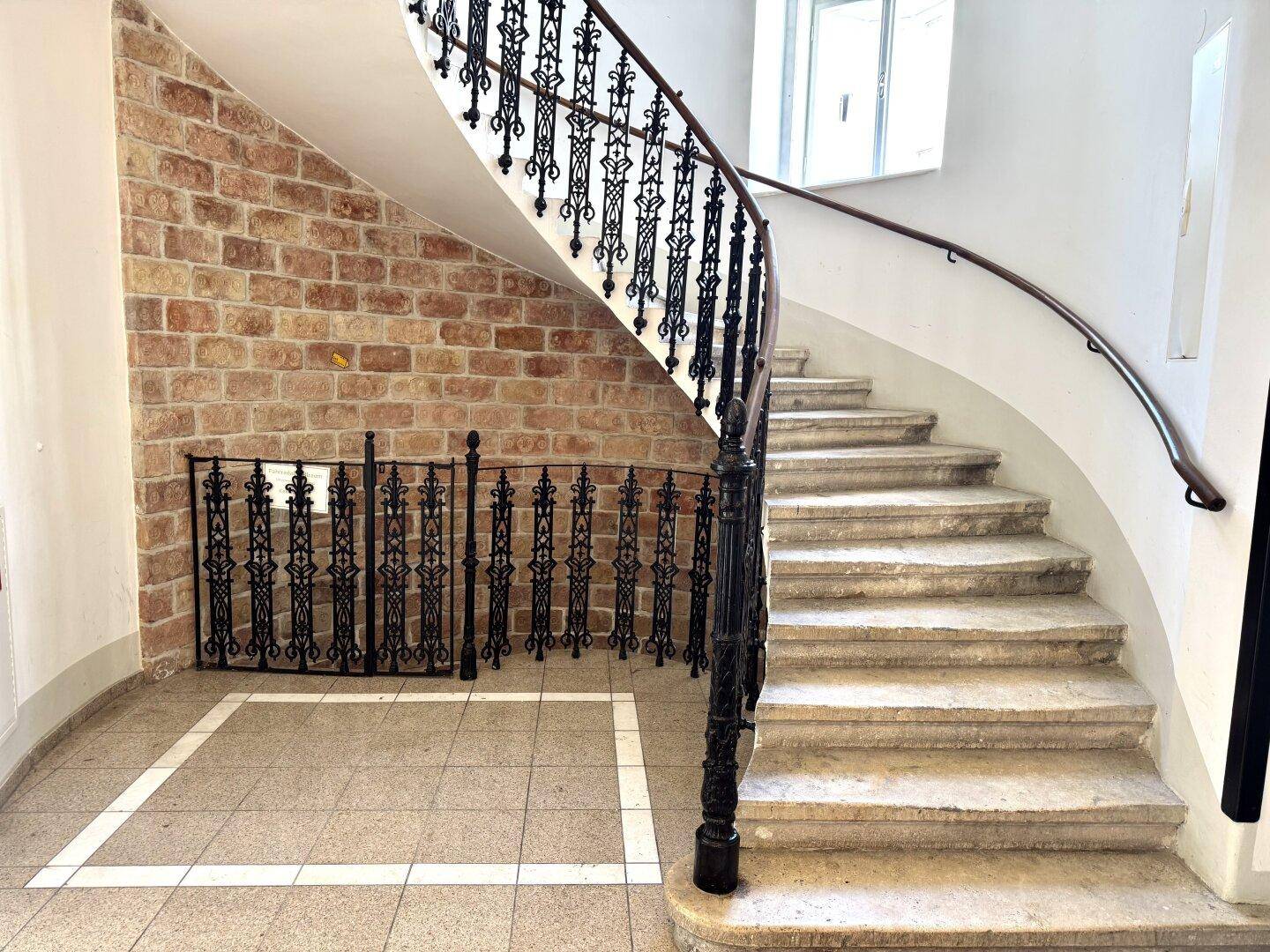 Historische Wendeltreppe mit schmiedeeisernem Geländer und einer charmanten Ziegelwand im Treppenhaus.