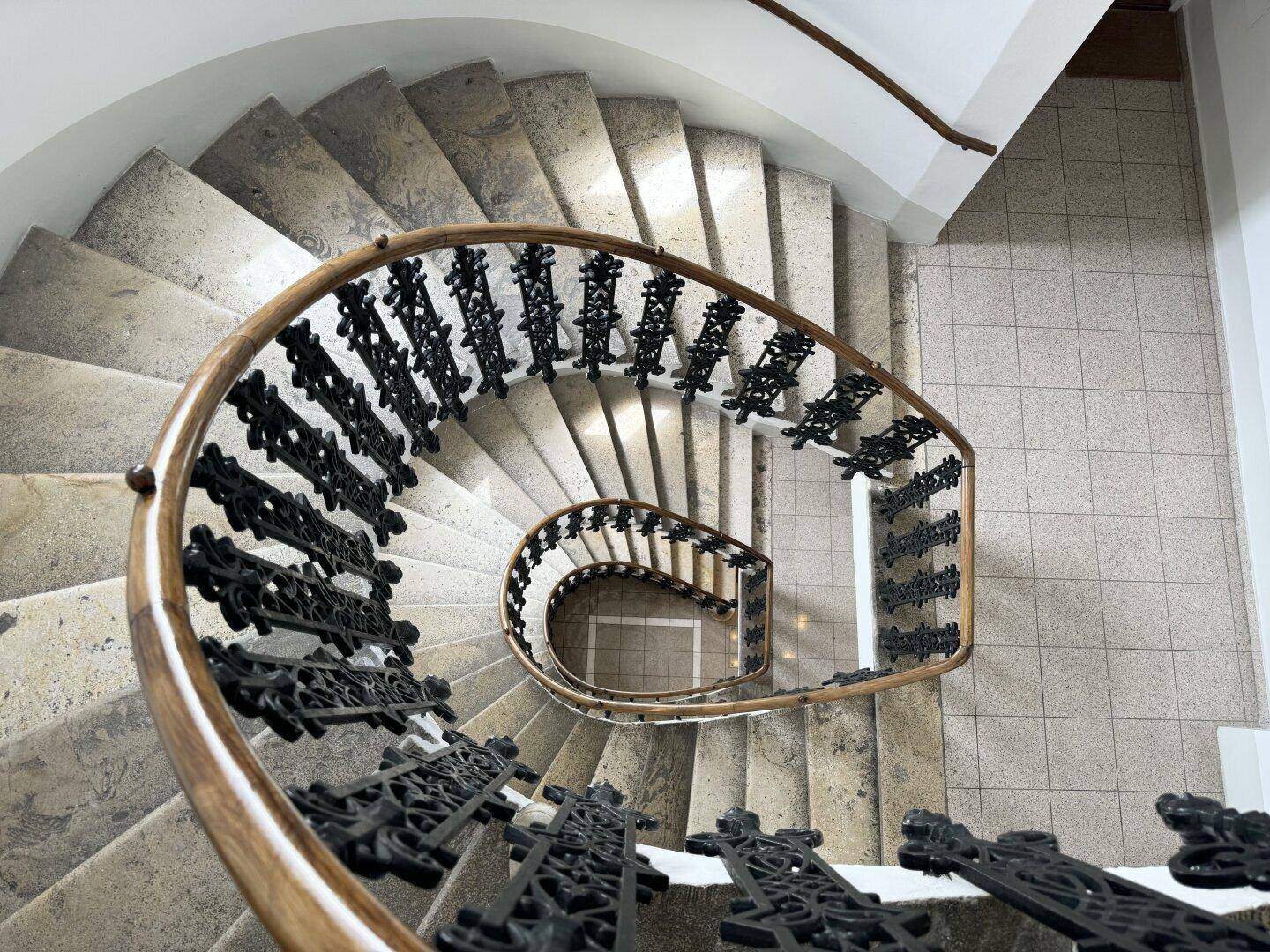 Beeindruckende Wendeltreppe mit schmiedeeisernem Geländer, von oben fotografiert, zeigt kunstvolle Details.