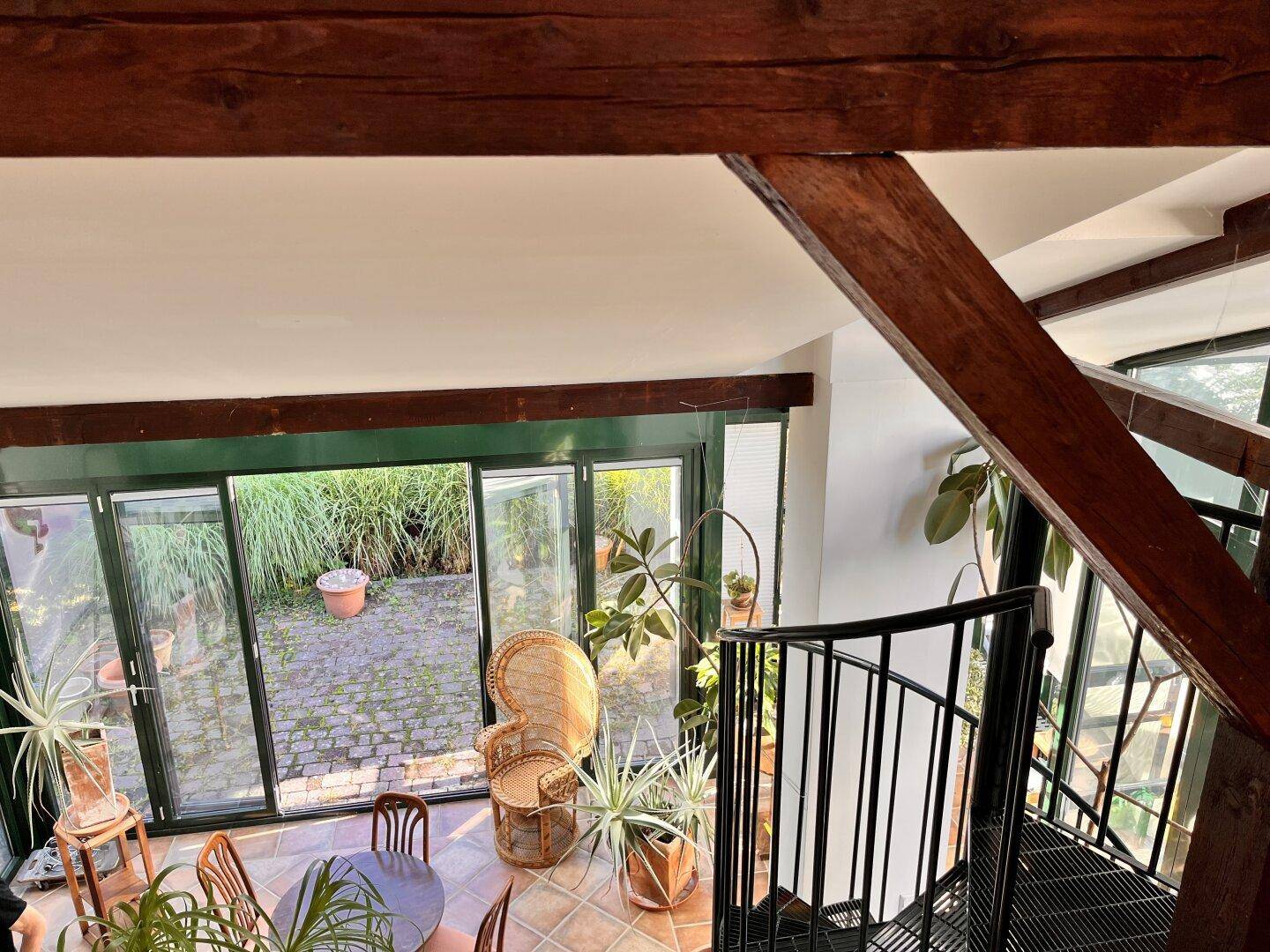 Blick von oben in den Wintergarten mit Holzbalken und Wendeltreppe.
