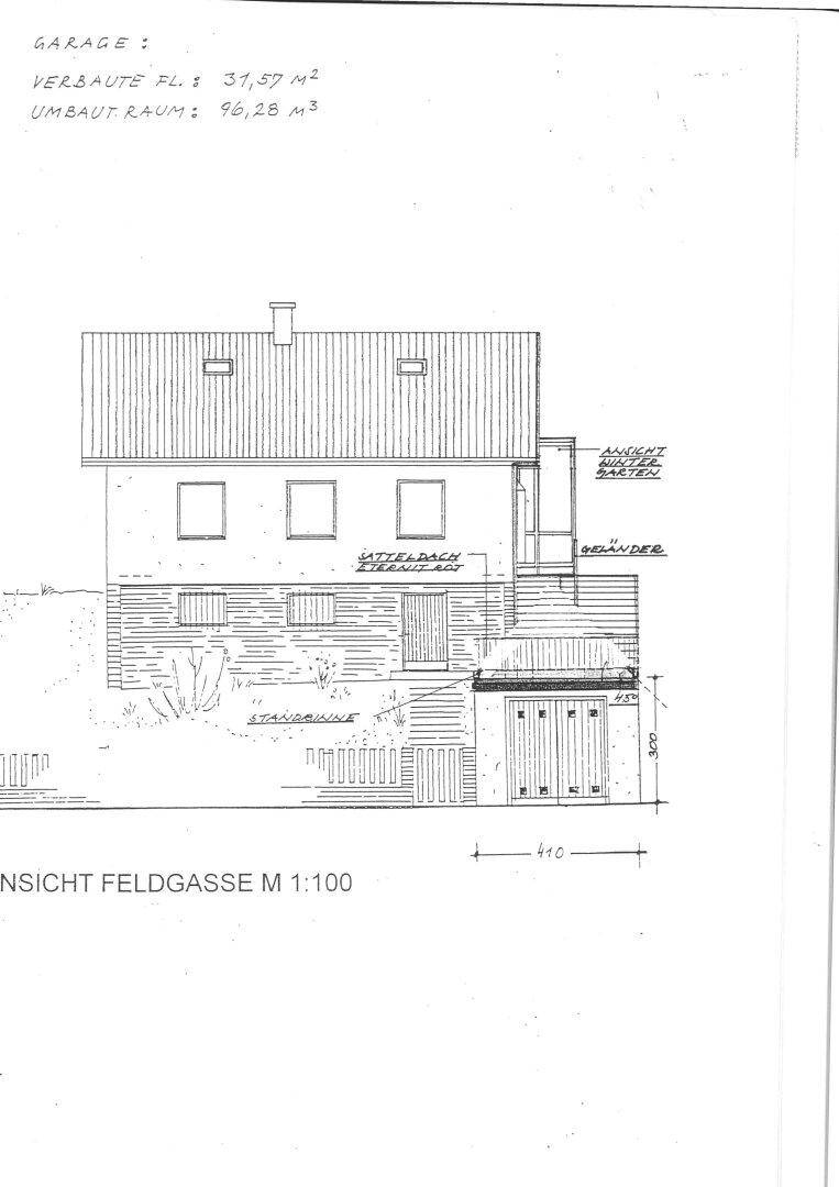 Vorderansicht des Hauses mit integrierter Garage und Balkon, von der Feldgasse aus gesehen.