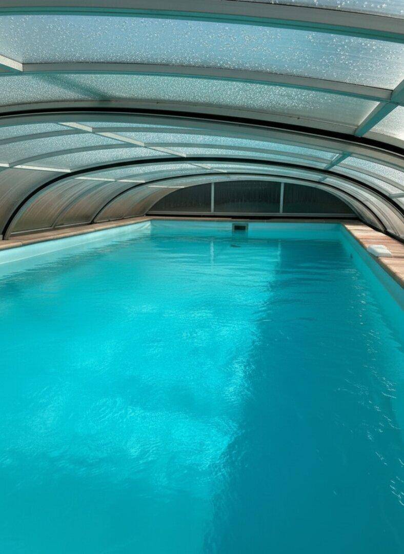 Überdachter Innenpool mit klarem Wasser und gewölbter Dachkonstruktion.