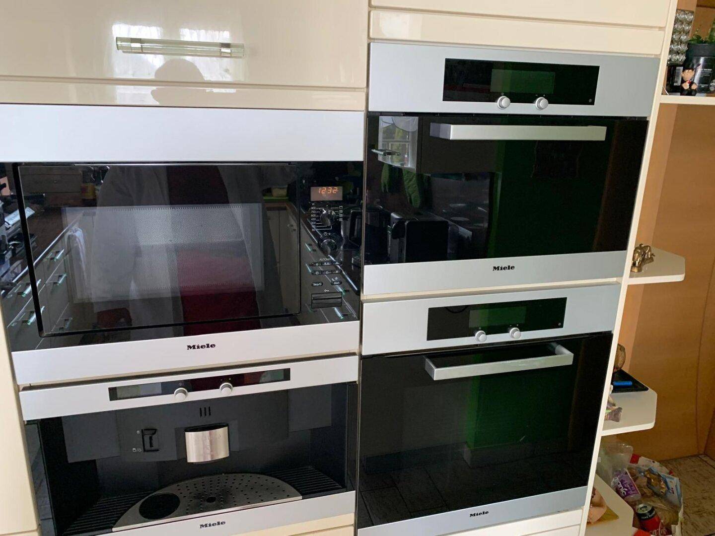 Hochwertige Einbaugeräte von Miele, darunter Backofen, Mikrowelle und Kaffeemaschine.