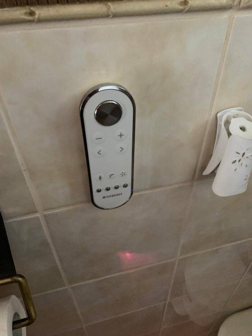 Nahaufnahme eines modernen Bedienfeldes für die Toilette an einer gefliesten Wand.