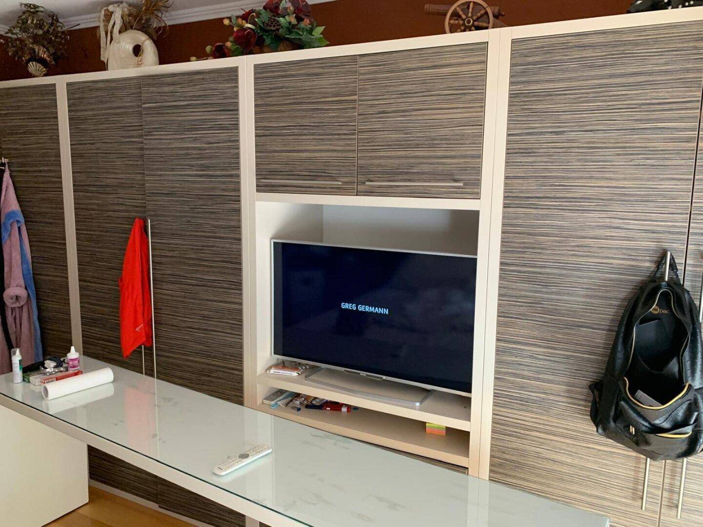 Moderne Einbauschrankwand mit integriertem Fernseher und viel Stauraum.