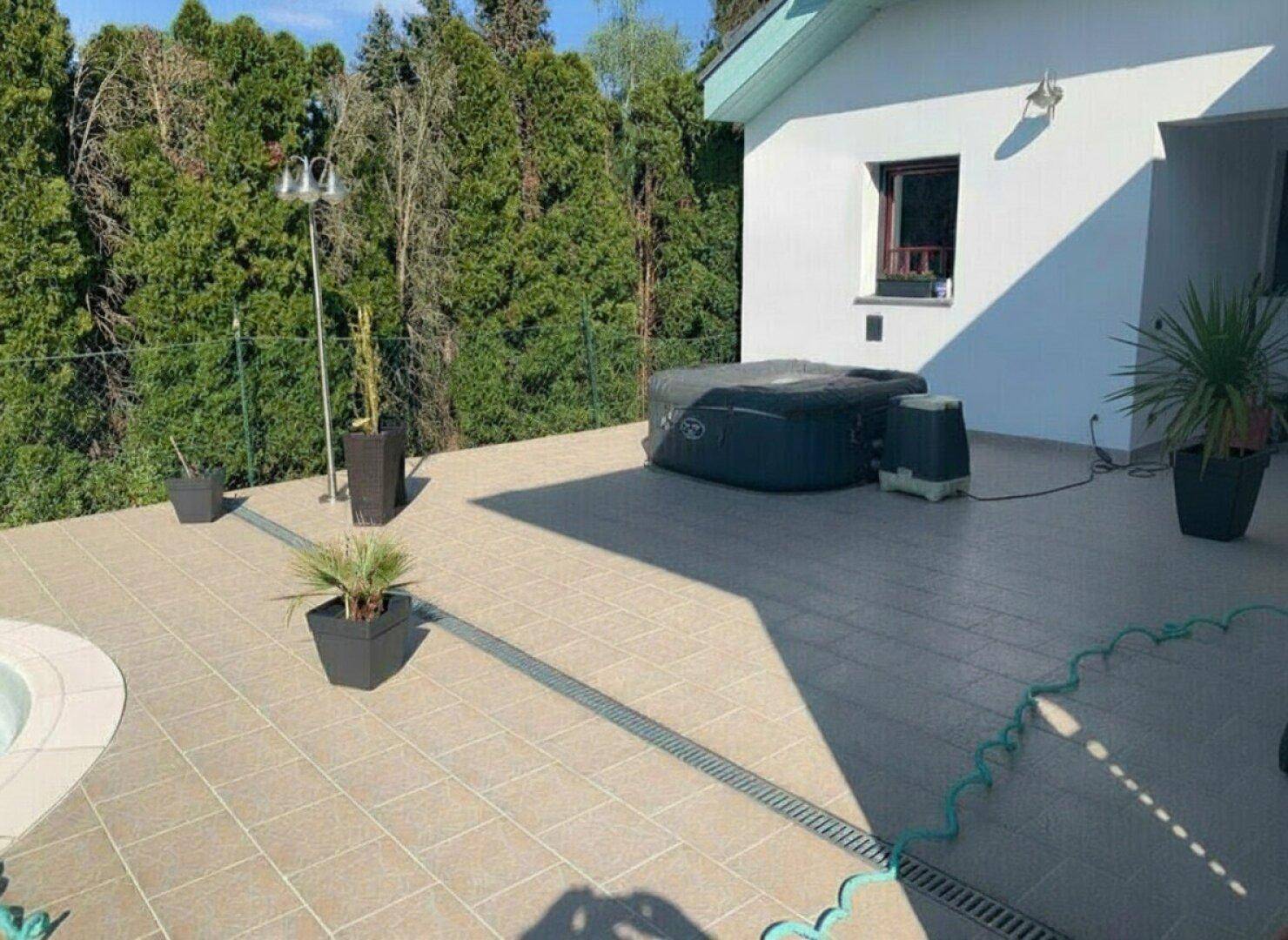Geräumige Terrasse mit einem aufblasbaren Whirlpool und Topfpflanzen für Entspannung im Freien.