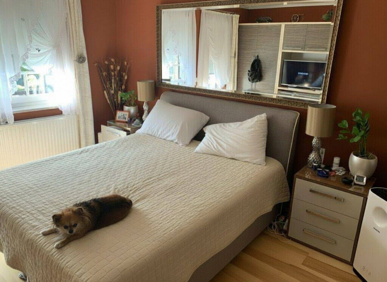 Gemütliches Schlafzimmer mit Doppelbett, Nachttischen und einem großen Spiegel über dem Bett.
