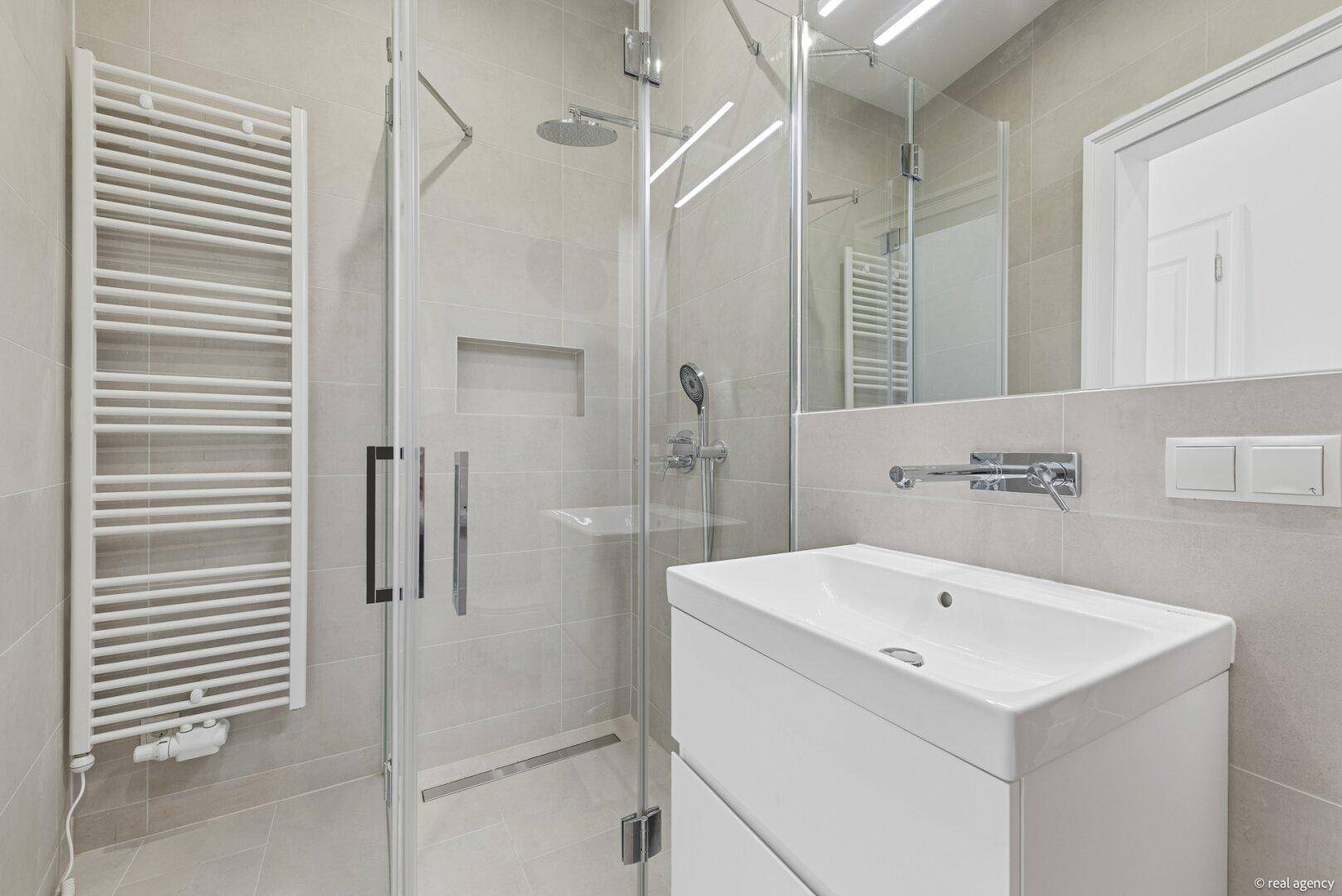 Modernes Badezimmer mit begehbarer Dusche, Einzelwaschbecken und beheiztem Handtuchhalter.