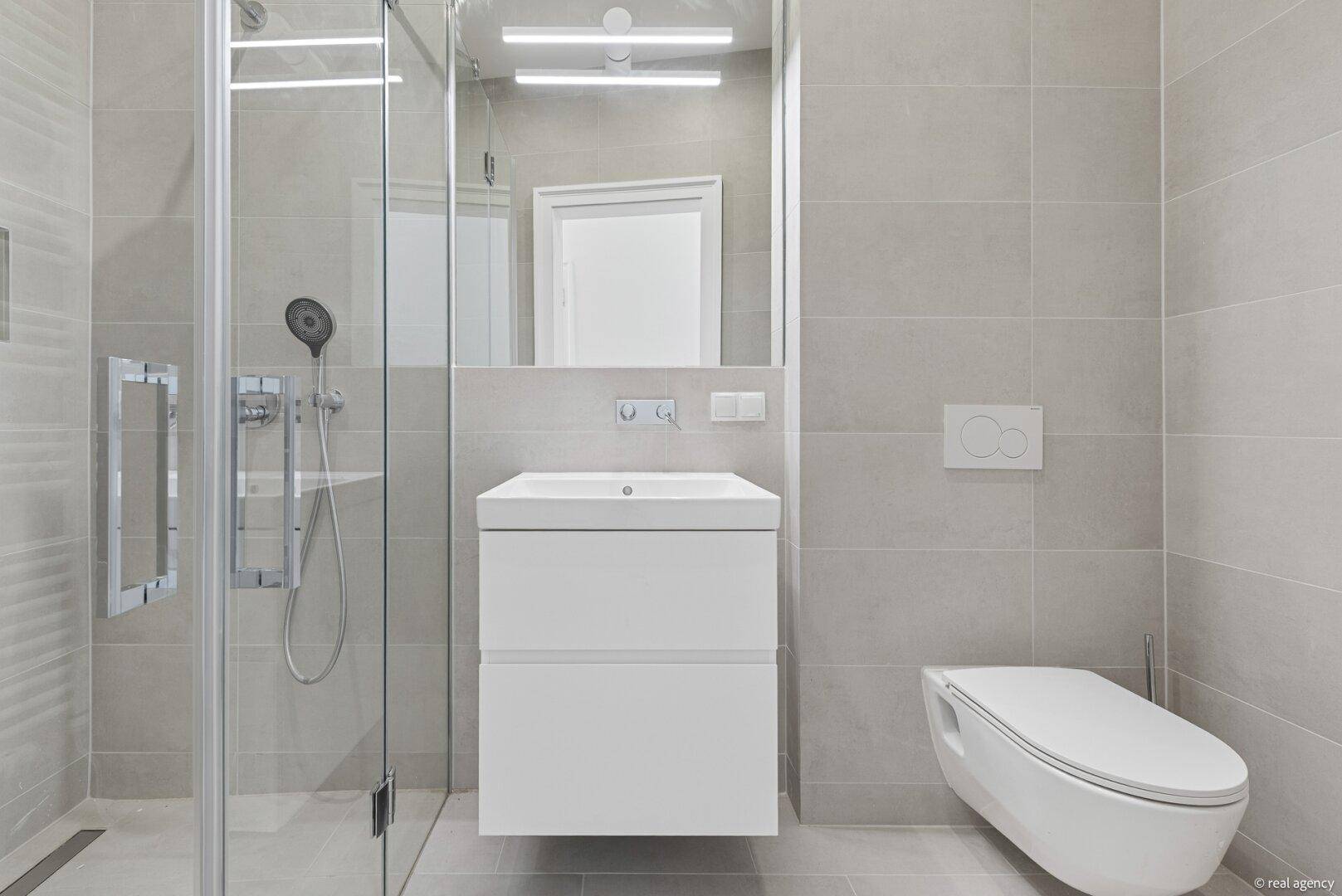 Helles Badezimmer mit moderner begehbarer Dusche, wandhängendem WC und eleganten Fliesen.
