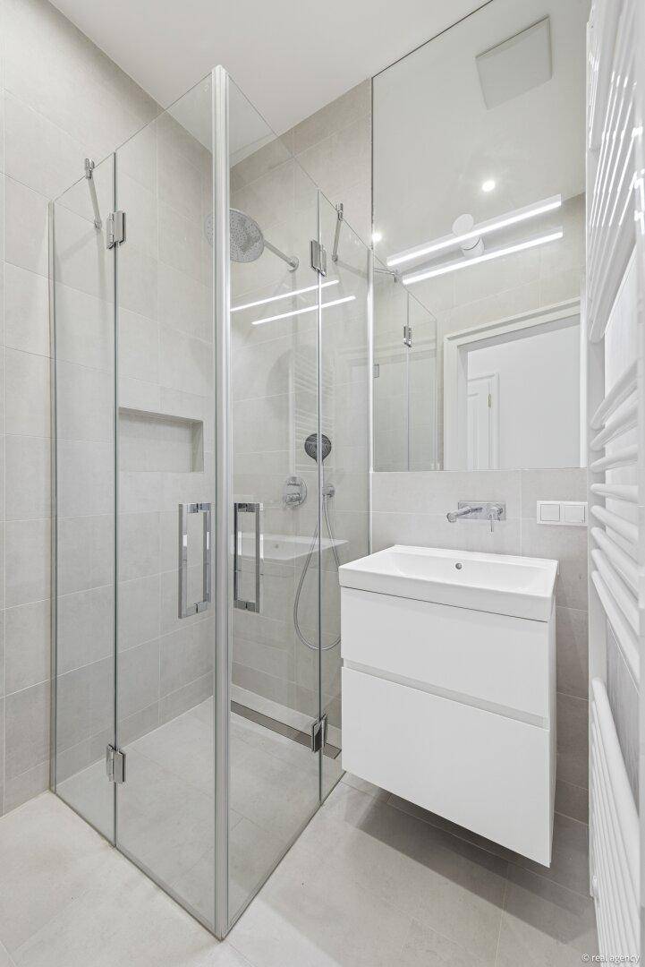 Modernes Badezimmer mit Glasdusche, schwebendem Waschtisch und beheiztem Handtuchhalter.