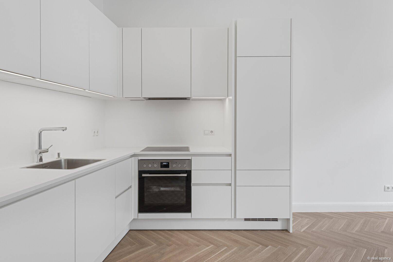 Detailansicht der modernen weißen Küchenzeile mit Spüle, Induktionskochfeld und Backofen.
