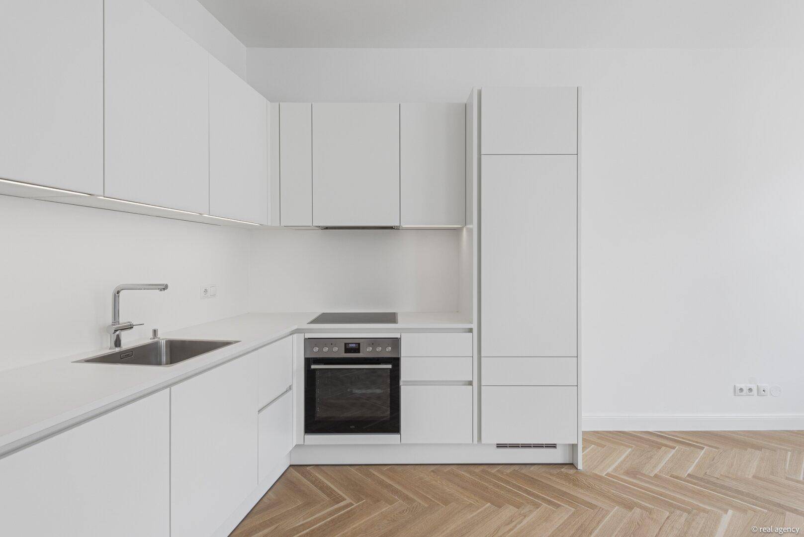 Detailansicht einer modernen weißen Einbauküche mit integriertem Backofen und Kochfeld.