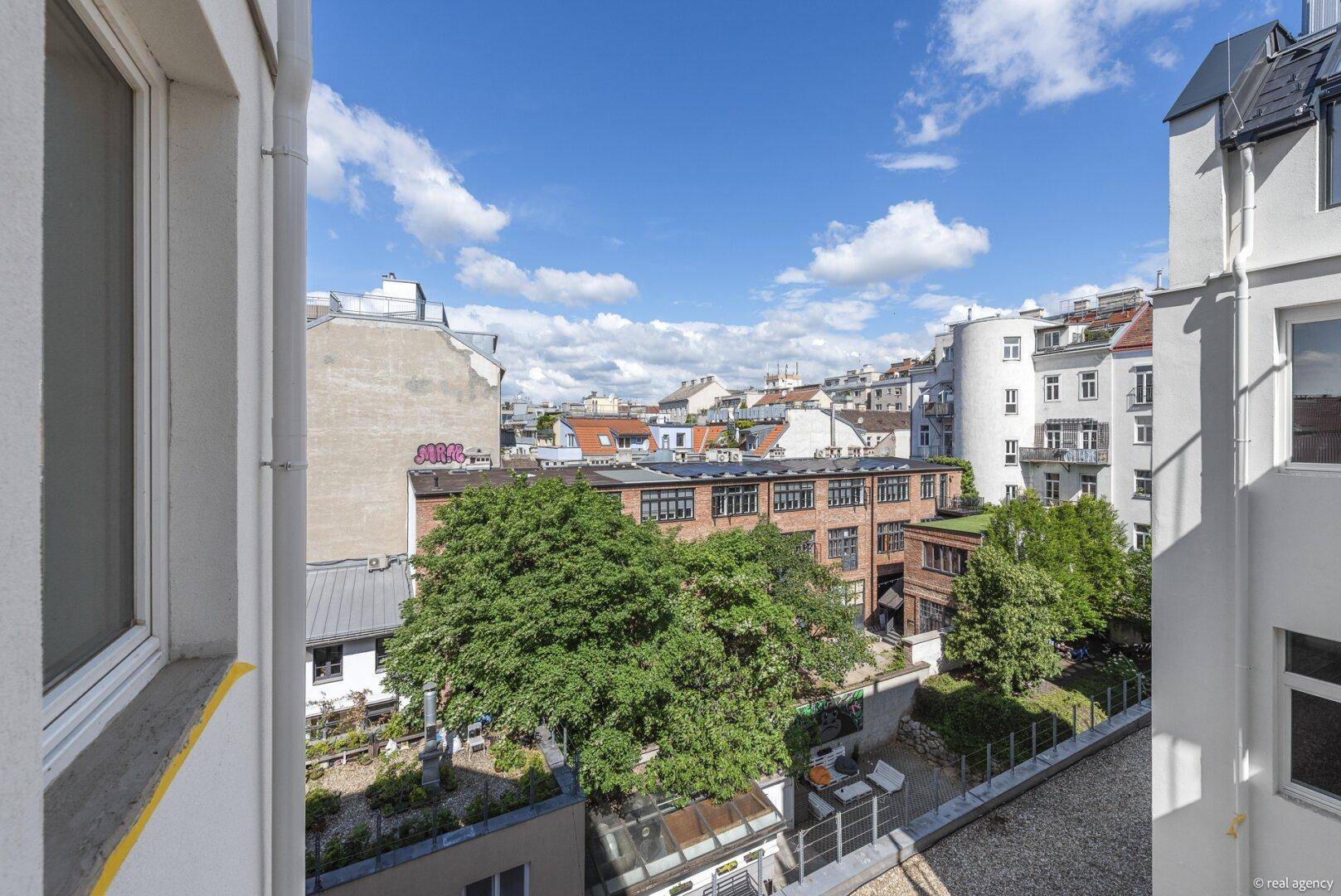Panoramablick über die Dächer der Stadt mit viel Grün und blauem Himmel.