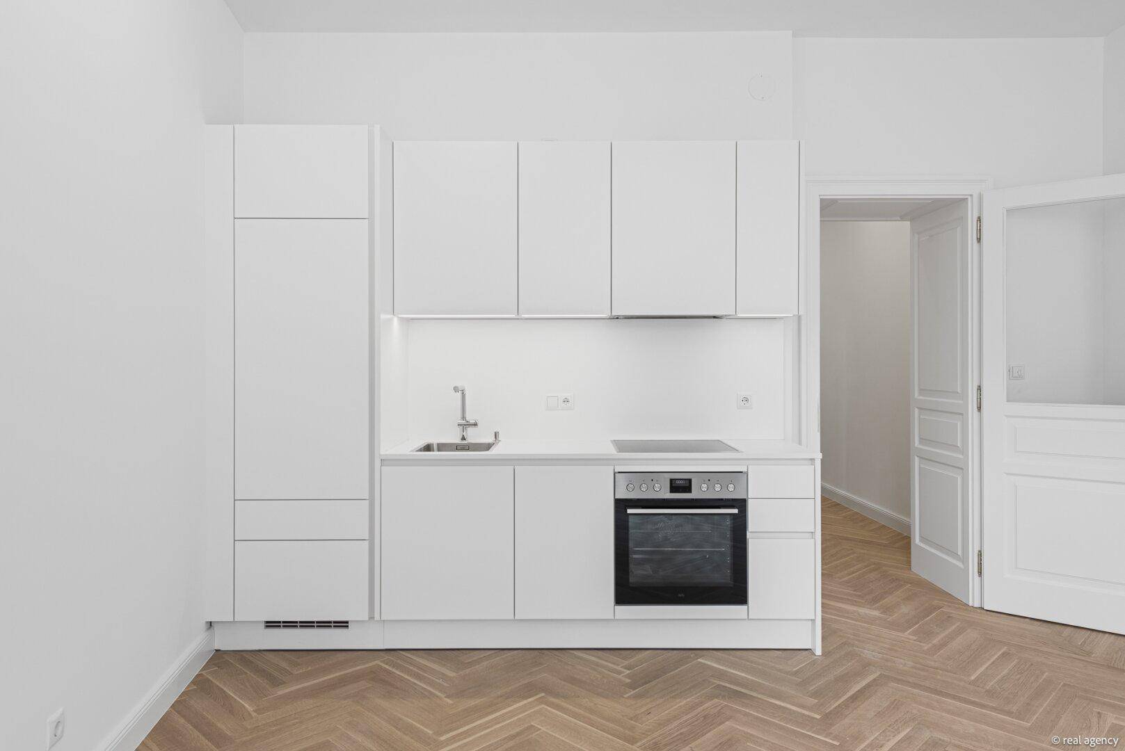 Kompakte, moderne Einbauküche in Weiß mit allen notwendigen Geräten, perfekt für offene Wohnbereiche.