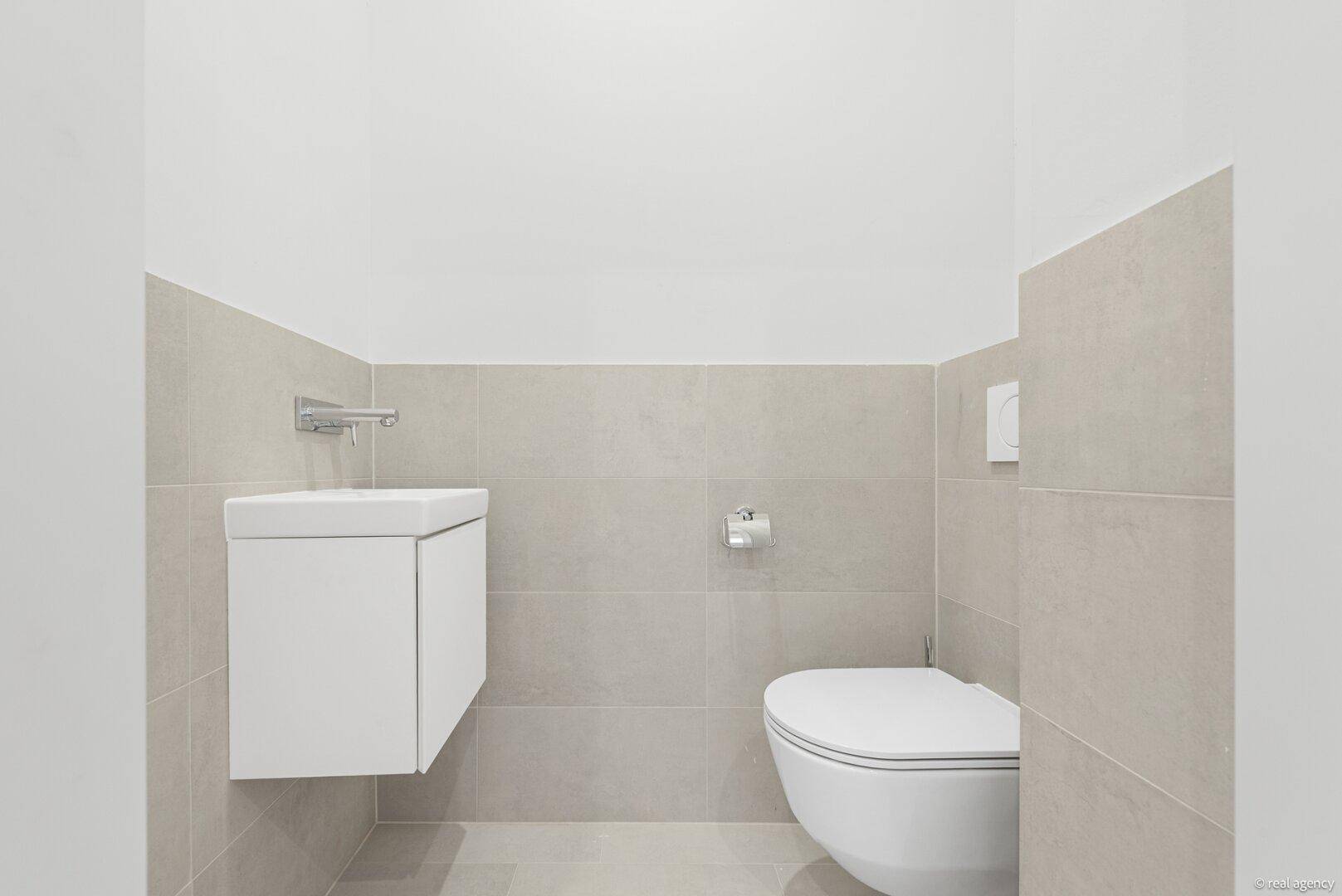 Modernes Gäste-WC mit wandhängender Toilette und kleinem Waschbecken.