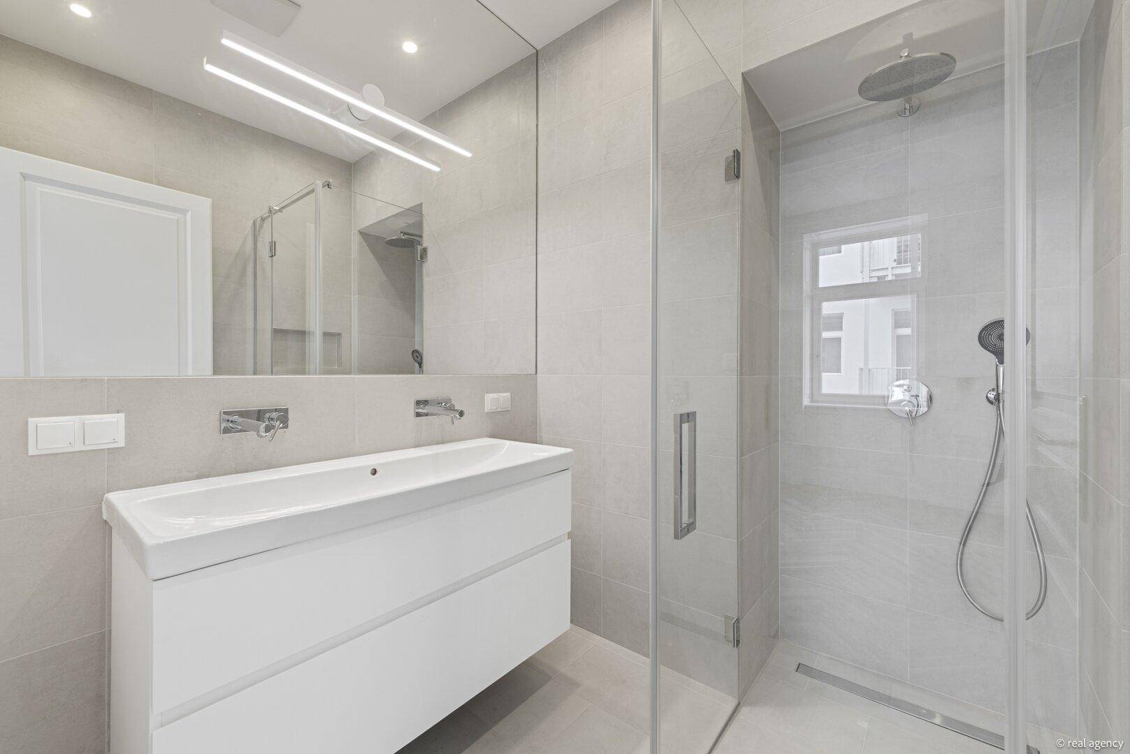 Modernes Badezimmer mit großem Waschtisch, Spiegel und begehbarer Dusche.