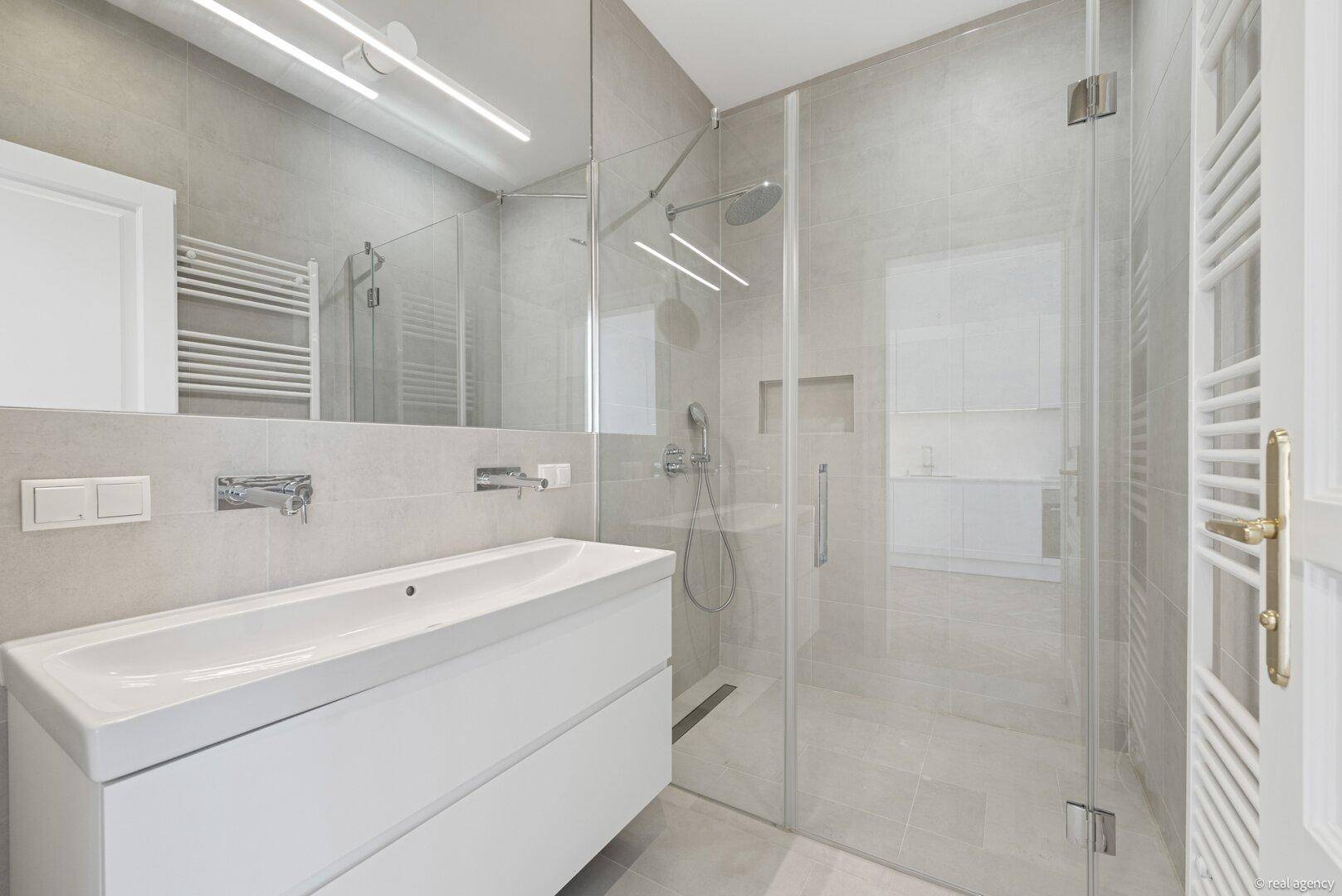 Modernes Badezimmer mit begehbarer Dusche, elegantem Waschtisch und beheiztem Handtuchhalter.