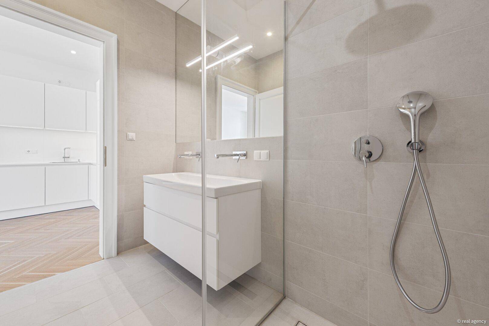 Geräumige begehbare Dusche im modernen Badezimmer mit Blick auf den Waschtisch.