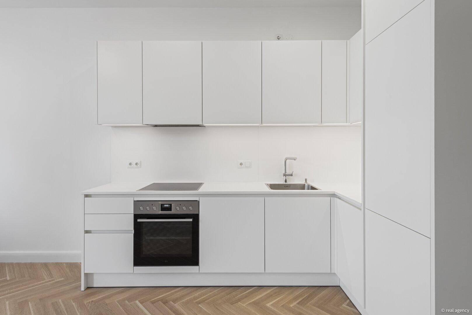 Detailansicht der modernen weißen Einbauküche mit integriertem Backofen und Kochfeld.