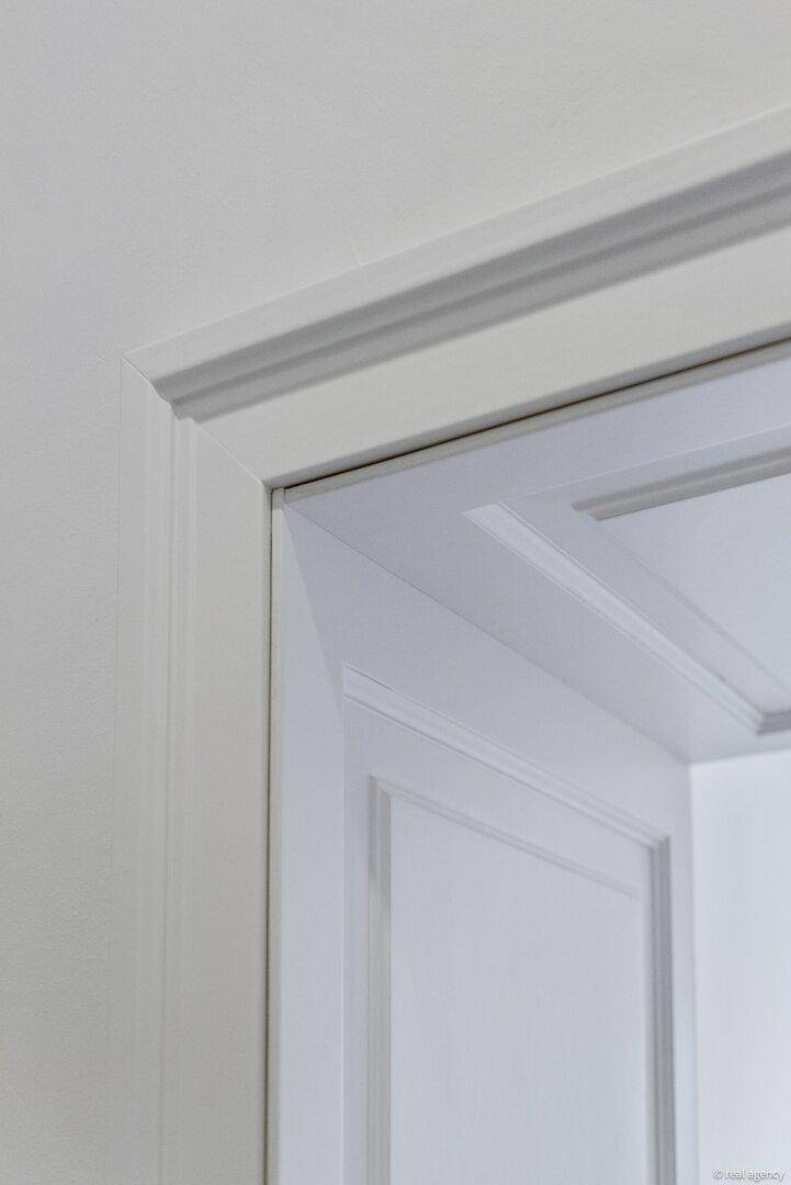 Detailaufnahme eines weißen Türrahmens mit klassischem Profil und glatter Oberfläche.