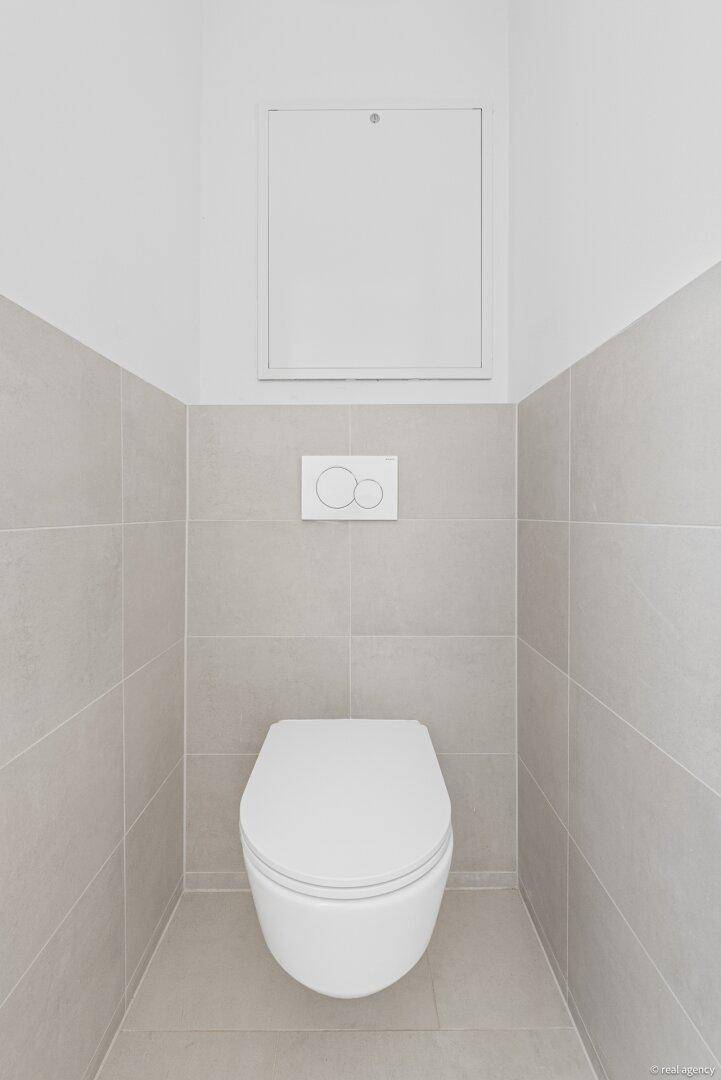 Wandhängendes WC in einem modern gefliesten Raum, ideal als Gäste-WC.