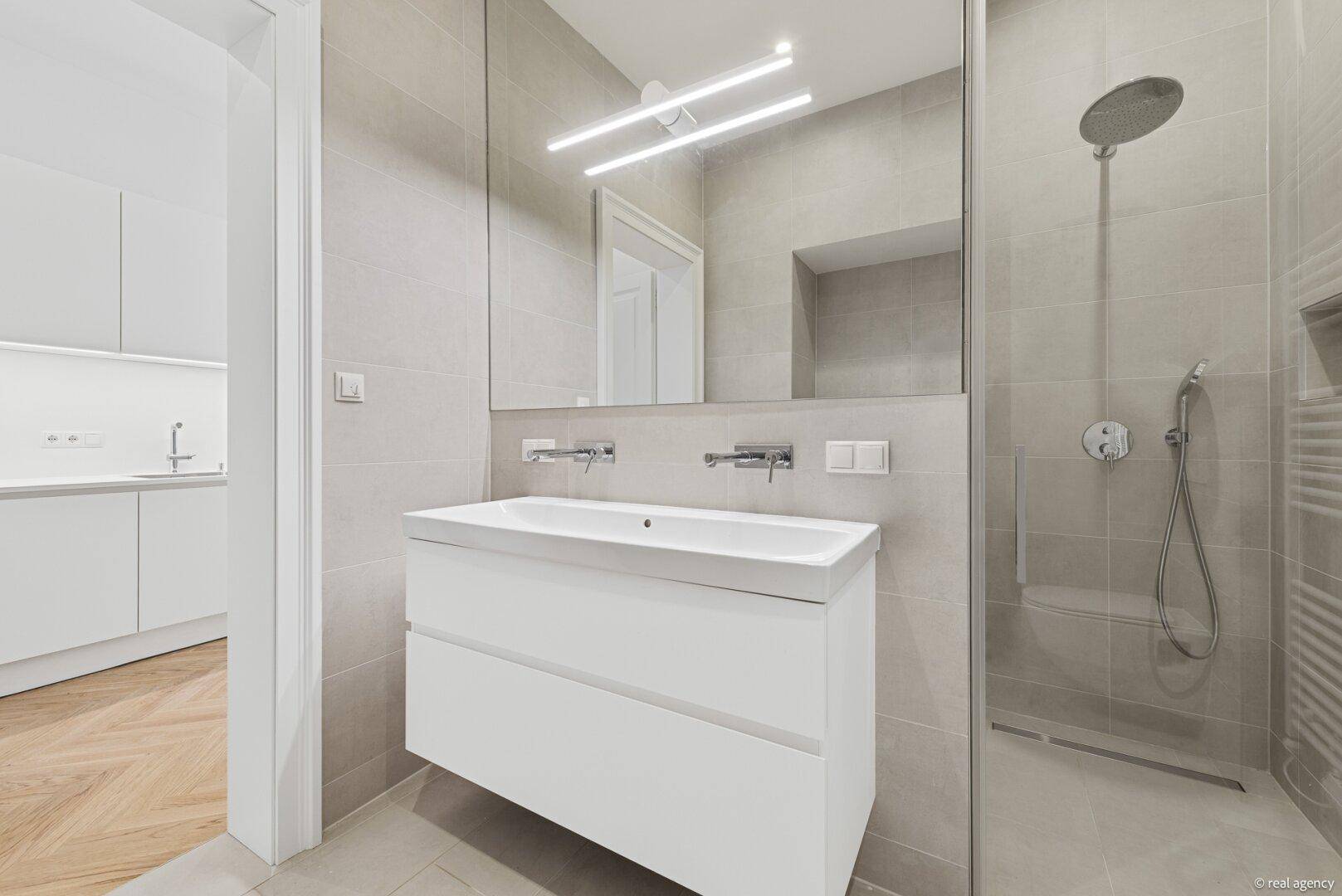 Modernes Badezimmer mit begehbarer Dusche, großem Waschtisch und großem Spiegel.