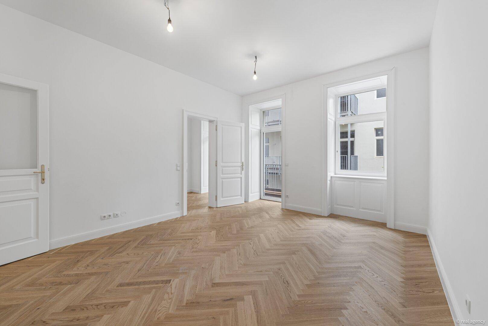 Geräumiges Zimmer mit Fischgrätparkett, hohen Decken und Zugang zum französischen Balkon.