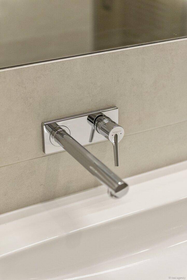 Elegante, wandmontierte Chromarmatur über einem modernen Waschbecken im Badezimmer.