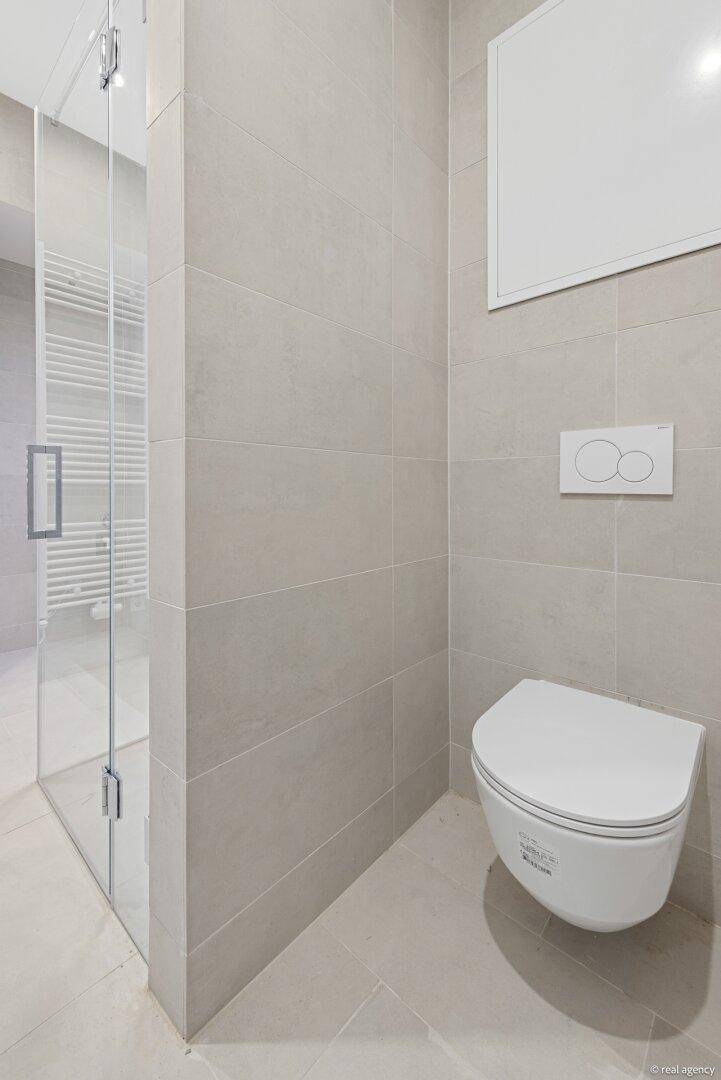 Elegantes Badezimmer mit wandhängender Toilette und geräumiger, begehbarer Dusche.