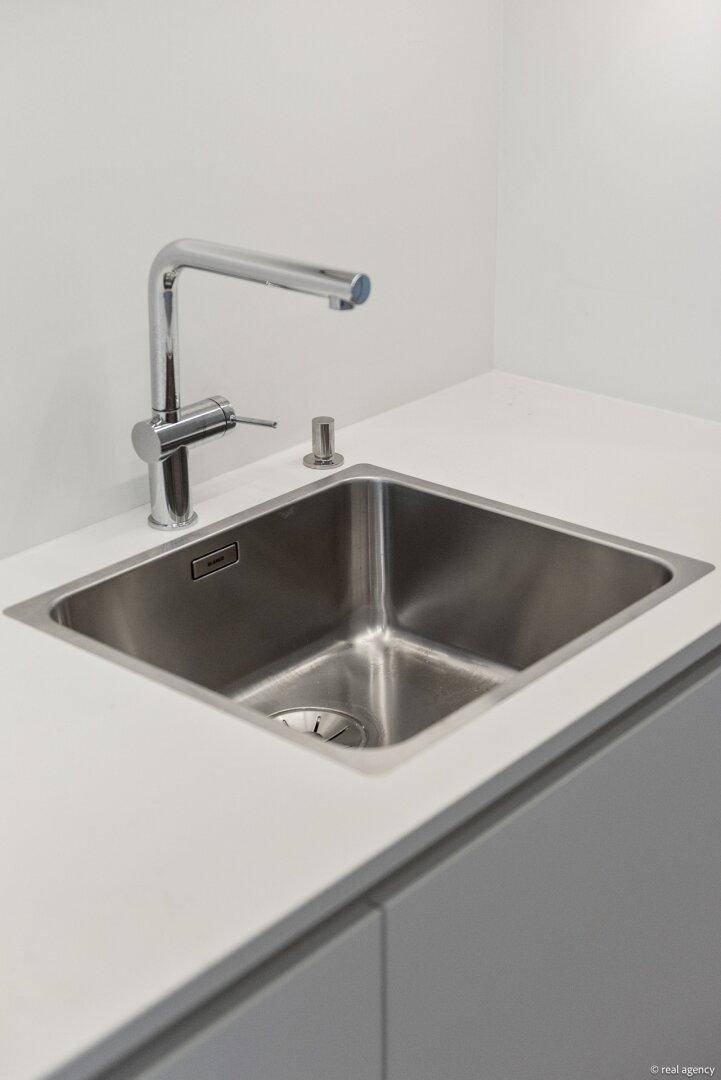 Edelstahlspüle mit modernem Wasserhahn in einer hellen Küche, die Sauberkeit und Effizienz bietet.