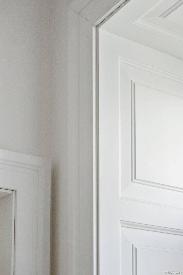 Detailansicht eines eleganten weißen Türrahmens und der Wand in einem modernen Interieur.