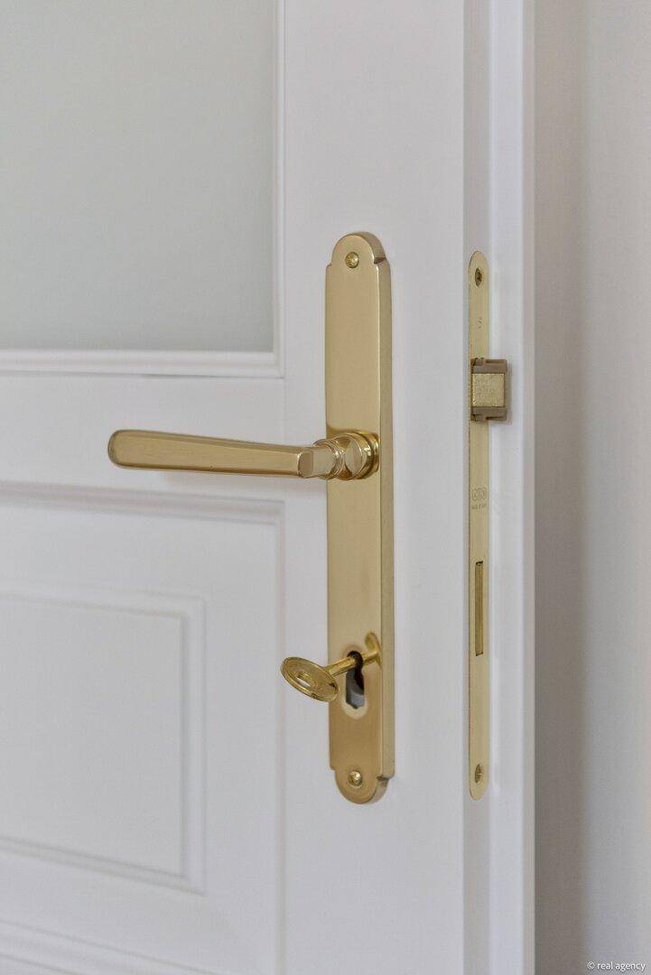 Nahaufnahme eines eleganten goldenen Türgriffs mit Schlüssel und passendem Beschlag.