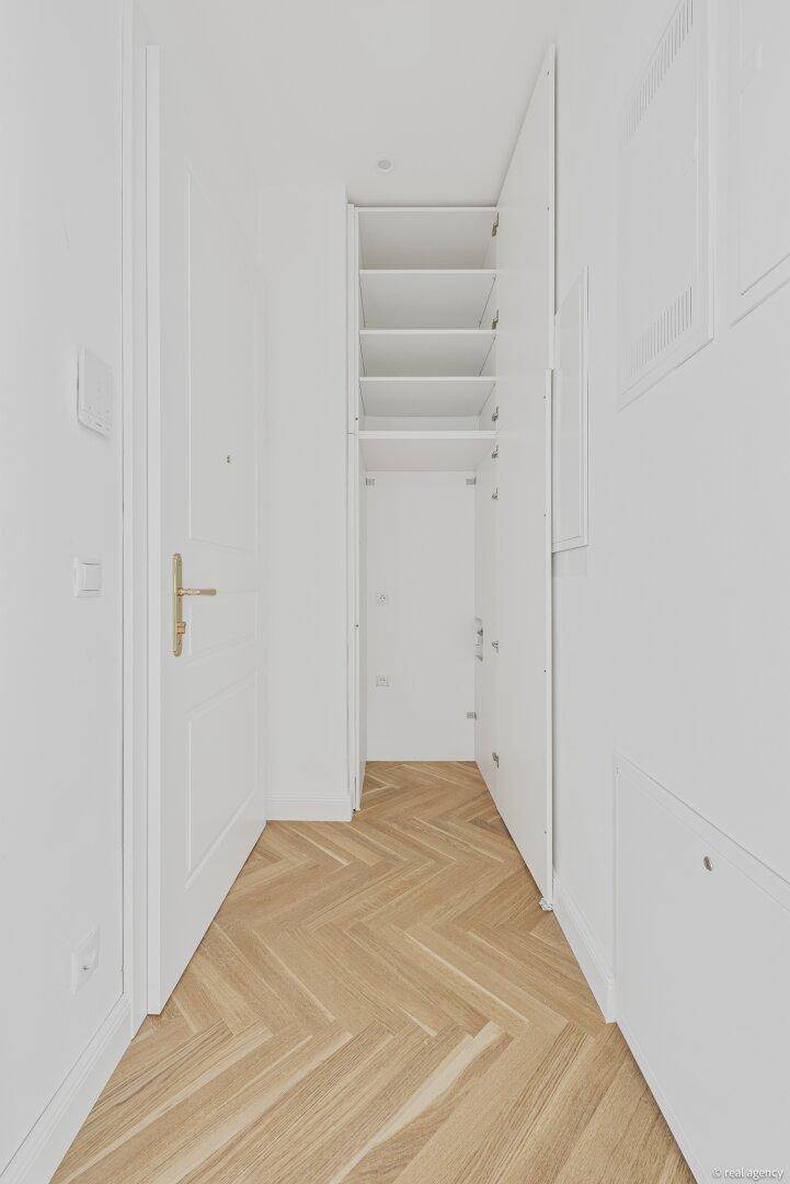 Heller Flur mit Fischgrätparkett und einem praktischen, offenen Einbauschrank.