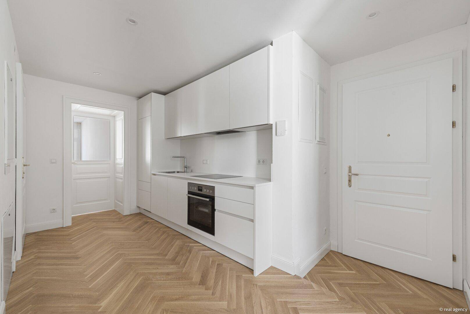 Helle, moderne Küche mit weißen Schränken und elegantem Fischgrätparkettboden.
