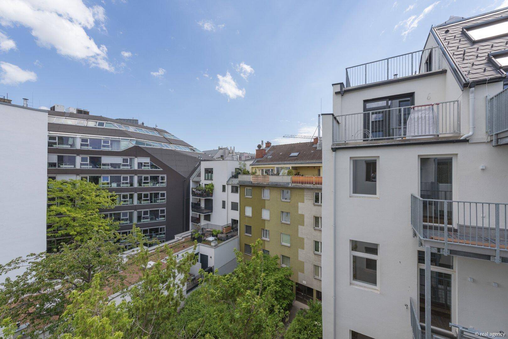 Blick auf die umliegenden Gebäude und grüne Bäume unter blauem Himmel.