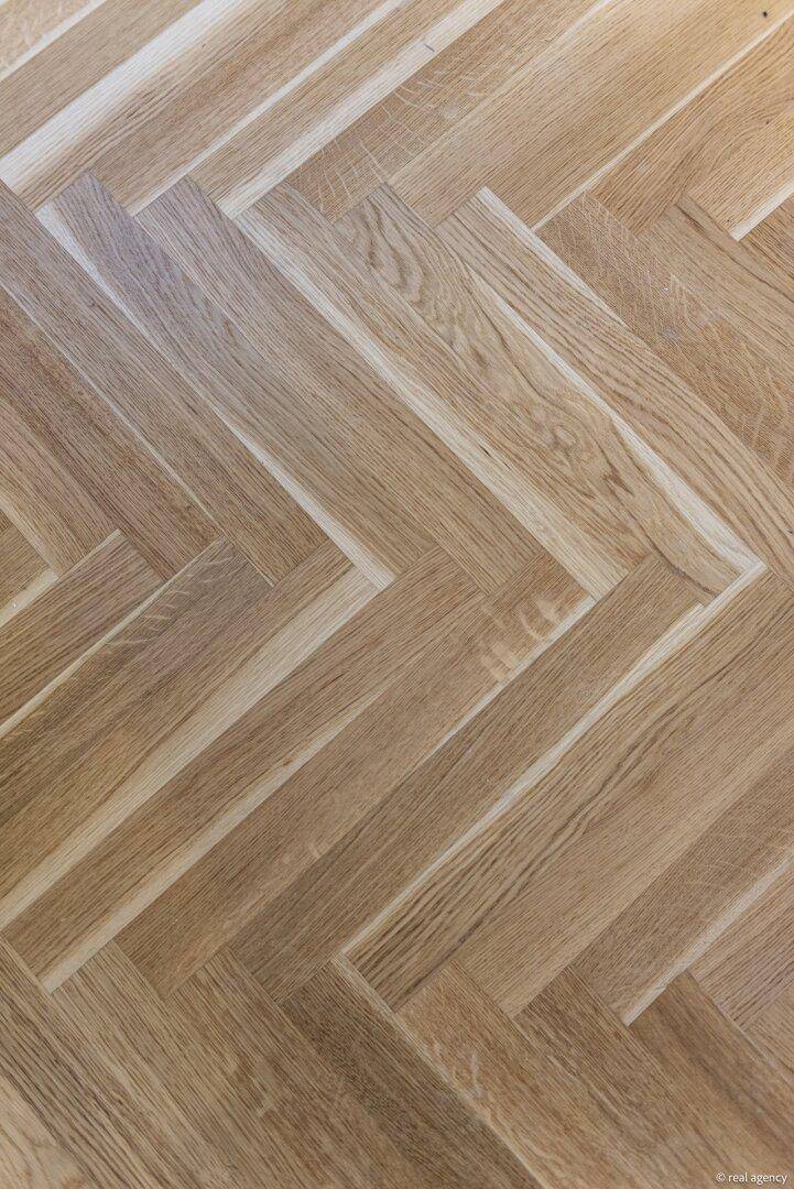 Nahaufnahme eines eleganten Fischgrätparkettbodens aus hellem Holz.
